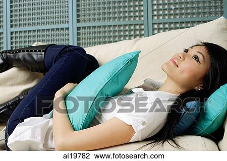 Young woman lying on sofa, looking away View Large Photo Image Stock Image - Young woman lying on sofa, looking away. Fotosearch