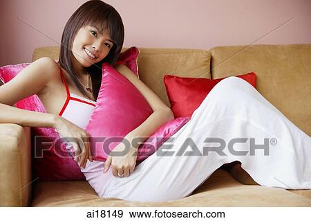 Young woman on sofa, smiling at camera View Large Photo Image Stock Photo - Young woman on sofa, smiling at camera. Fotosearch