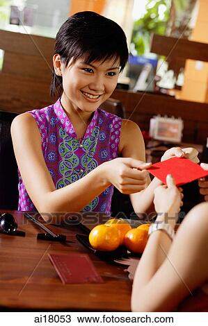 Young woman passing a red packet to person facing her View Large Photo Image Stock Image - Young woman passing a red packet to person facing her. Fotosearch