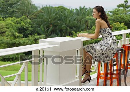 Young woman sitting on bar stool, leaning on railing View Large Photo Image Stock Image - Young woman sitting on bar stool, leaning on railing. Fotosearch