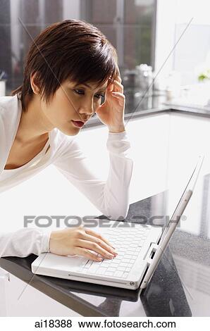 Young woman using laptop in kitchen View Large Photo Image Stock Photo - Young woman using laptop in kitchen. Fotosearch