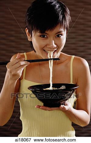 Young woman with chopsticks, eating noodles, looking at camera View Large Photo Image Stock Photo - Young woman with chopsticks, eating noodles, looking at camera. Fotosearch