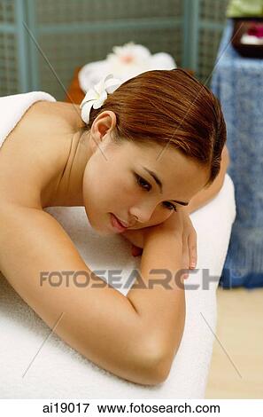 Young woman with flower in hair, lying on massage table, leaning on arms View Large Photo Image Stock Photo - Young woman with flower in hair, lying on massage table, leaning on arms. Fotosearch