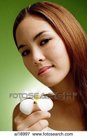 Young woman with long hair holding Frangipani flower View Large Photo Image Stock Photo - Young woman with long hair holding Frangipani flower. Fotosearch