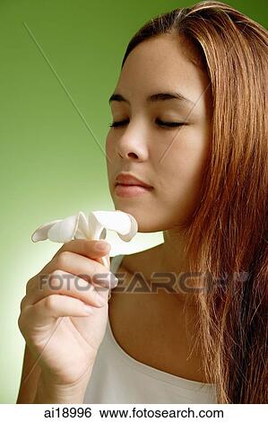 Stock Photograph - Young woman with long hair smelling flower. Fotosearch