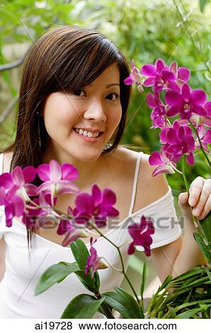 Young woman with orchid plant, smiling at camera View Large Photo Image Stock Photo - Young woman with orchid plant, smiling at camera. Fotosearch