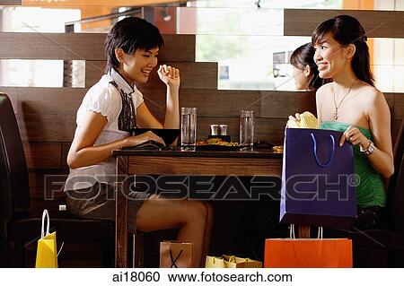 Young women in restaurant, looking at shopping bags View Large Photo Image Stock Image - Young women in restaurant, looking at shopping bags. Fotosearch