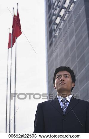 A businessman stands in front of a building with flags View Large Photo Image Stock Image - A businessman stands in front of a building with flags. Fotosearch