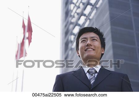 A businessman stands in front of a building with flags View Large Photo Image Stock Photography - A businessman stands in front of a building with flags. Fotosearch