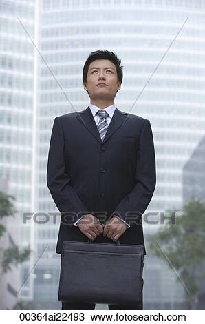 A businessman stands in the city with a briefcase View Large Photo Image Stock Image - A businessman stands in the city with a briefcase. Fotosearch