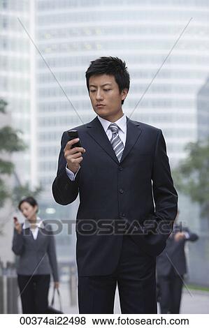 A businessman uses his cellphone View Large Photo Image Stock Photo - A businessman uses his cellphone. Fotosearch