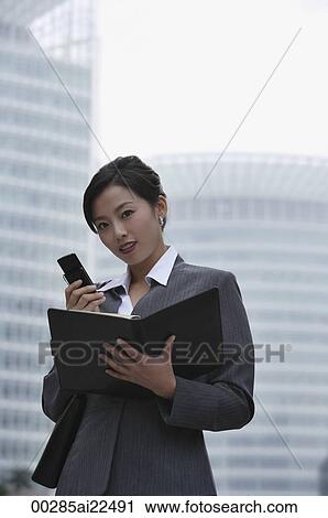 A businesswoman looks at the camera as she uses her cellphone View Large Photo Image Stock Image - A businesswoman looks at the camera as she uses her cellphone. Fotosearch