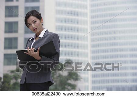 A businesswoman looks at the camera as she holds a folder View Large Photo Image Stock Image - A businesswoman looks at the camera as she holds a folder. Fotosearch