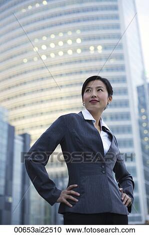 A businesswoman stands in front of a skyscraper View Large Photo Image Stock Image - A businesswoman stands in front of a skyscraper. Fotosearch