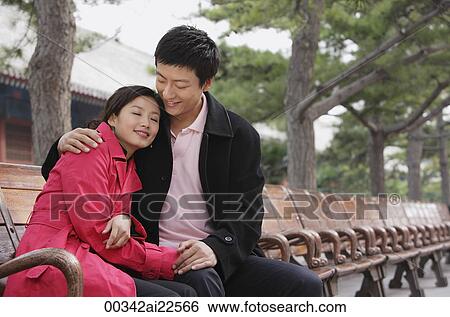 A couple cuddle as they sit down View Large Photo Image Stock Photograph - A couple cuddle as they sit down. Fotosearch
