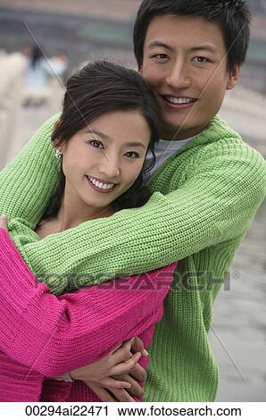 Stock Image - A couple have their arms around each other as they look at the camera. Fotosearch