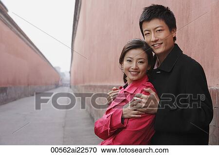A couple have their arms around each other as they look at the camera View Large Photo Image Stock Image - A couple have their arms around each other as they look at the camera. Fotosearch