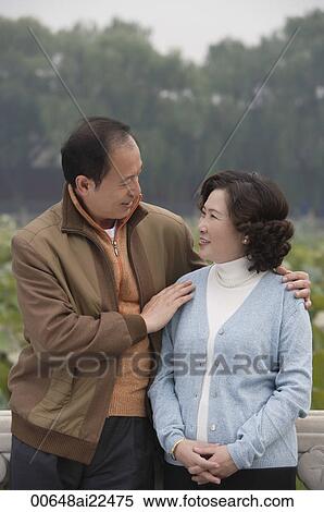 Stock Photography - A couple look at each other as they stand outdoors. Fotosearch