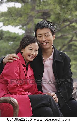 A couple look at the camera as they sit down and cuddle View Large Photo Image Stock Photography - A couple look at the camera as they sit down and cuddle. Fotosearch