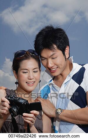 A couple look at the photos they have taken View Large Photo Image Stock Photograph - A couple look at the photos they have taken. Fotosearch