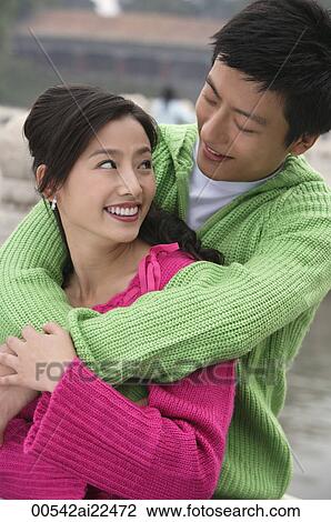Stock Image - A couple smile as they have their arms around each other. Fotosearch