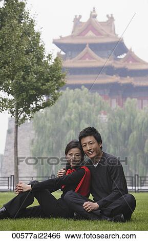 Stock Photograph - A couple smile at the camera as they sit in front of The Forbidden City, Beijing. Fotosearch