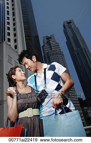 A couple walk with their arms around each other as they shop View Large Photo Image Stock Photo - A couple walk with their arms around each other as they shop. Fotosearch