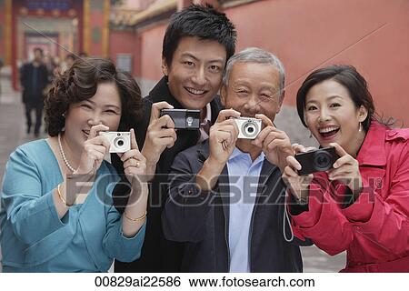Stock Photograph - A family all hold up their cameras to take photos. Fotosearch