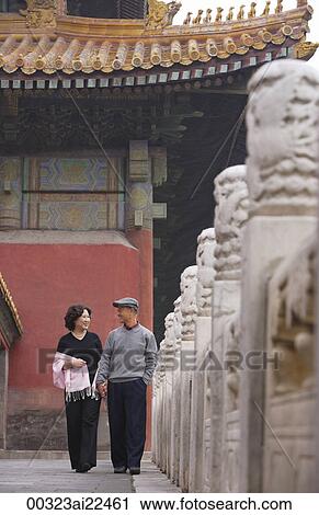 Stock Image - A man and woman hold hands as they walk together. Fotosearch