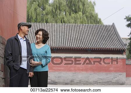 Picture - A man and woman link arms as they walk together. Fotosearch