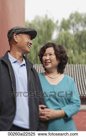 Stock Photography - A man and woman link arms as they walk together. Fotosearch