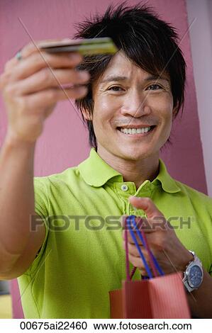 A man holds out his credit card as he holds shopping bags View Large Photo Image Stock Image - A man holds out his credit card as he holds shopping bags. Fotosearch