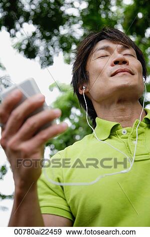 Stock Photo - A man listens to music with headphones. Fotosearch