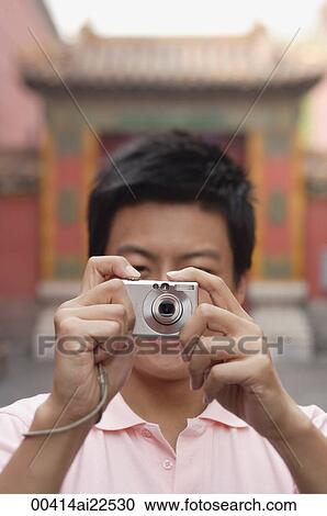 Stock Image - A man looks at the camera and takes a photo. Fotosearch