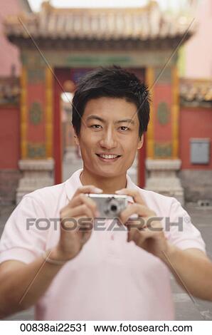 Stock Image - A man looks at the camera and takes a photo. Fotosearch