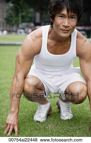 Stock Photo - A man looks at the camera as he gets ready to exercise in the park. Fotosearch
