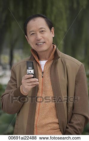 Stock Photo - A man looks at the camera as he uses his cellphone. Fotosearch