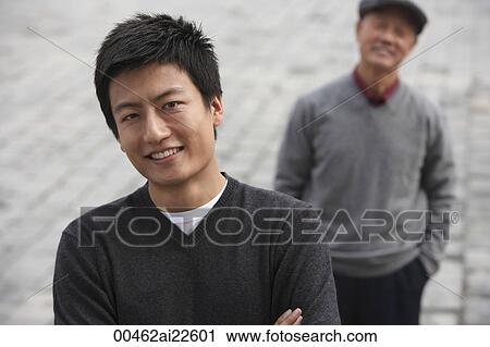 Stock Image - A man looks at the camera as his grandfather stands in the background. Fotosearch