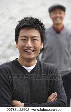 Stock Image - A man looks at the camera as his grandfather stands in the background. Fotosearch