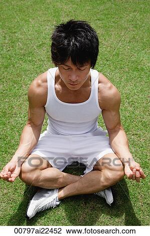 Stock Image - A man sits and meditates in the park. Fotosearch