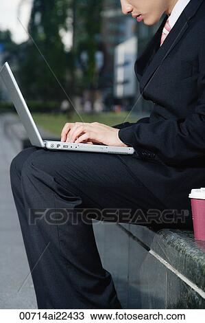 A man sits and uses his laptop outdoors View Large Photo Image Stock Image - A man sits and uses his laptop outdoors. Fotosearch