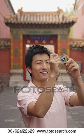 Stock Photo - A man smiles as he takes photos. Fotosearch