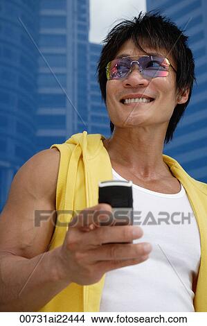 Picture - A man smiles as he uses his cellphone. Fotosearch