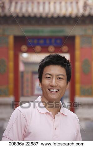 Stock Photo - A man smiles at the camera as he stands in front of a doorway. Fotosearch