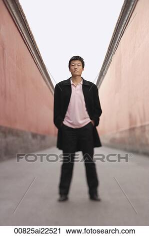 Stock Image - A man stands with his hands in his pockets. Fotosearch