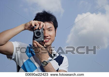 A man takes a photo looking at the camera View Large Photo Image Stock Image - A man takes a photo looking at the camera. Fotosearch