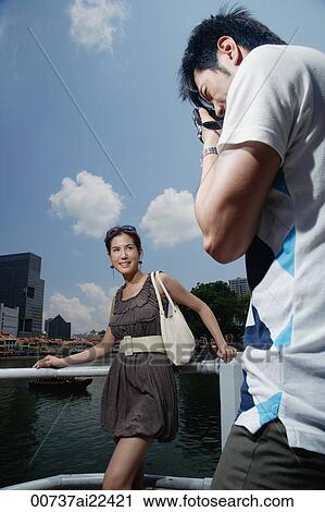 A man takes a photo of his girlfriend with the city in the background View Large Photo Image Stock Image - A man takes a photo of his girlfriend with the city in the background. Fotosearch