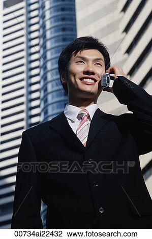 A man talks on his cellphone as he stands in the city View Large Photo Image Stock Image - A man talks on his cellphone as he stands in the city. Fotosearch