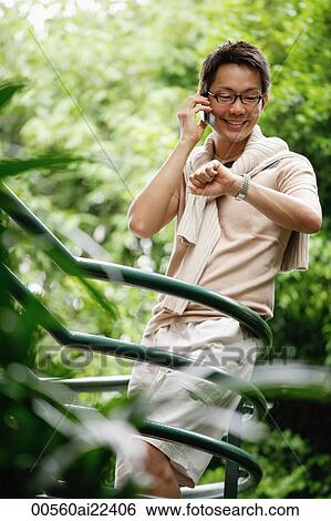 A man uses his cellphone as he stands on stairs surrounded by trees View Large Photo Image Stock Photograph - A man uses his cellphone as he stands on stairs surrounded by trees. Fotosearch
