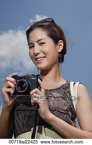 A woman looks at the camera as she holds her own camera View Large Photo Image Stock Photography - A woman looks at the camera as she holds her own camera. Fotosearch